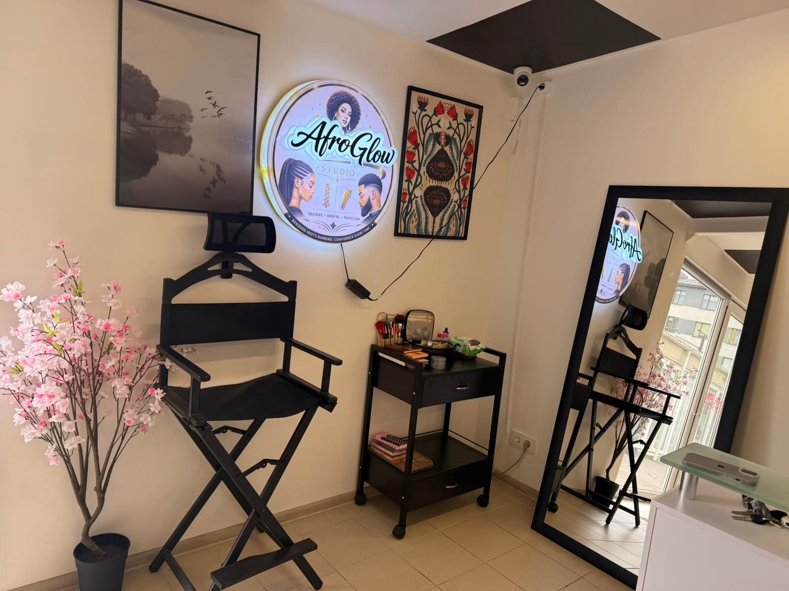 Afroglow Studio in Vilnius — illuminated AfroGlow Studio sign above the styling chair and makeup station
